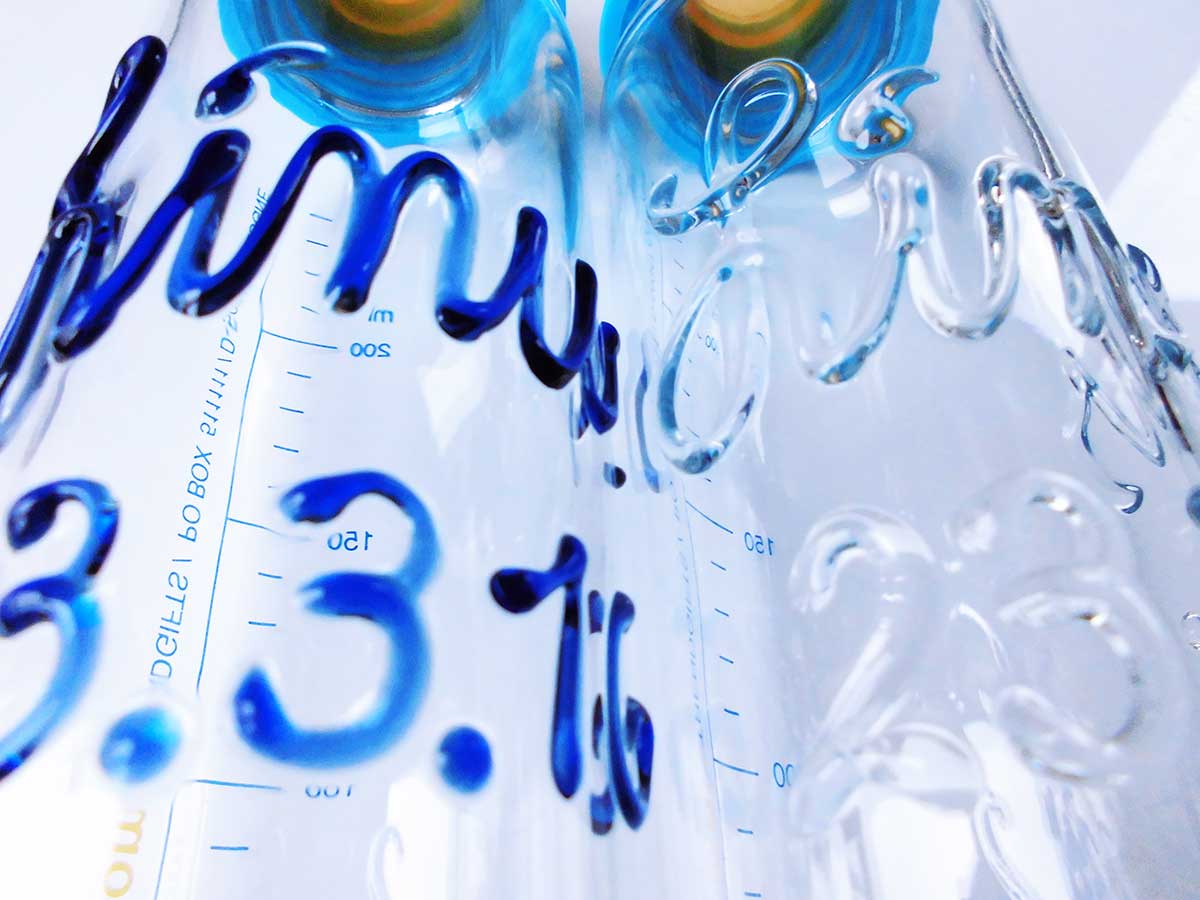 Glasgravuren der Babyflasche mit Namen in blauer und glasklarer Schrift