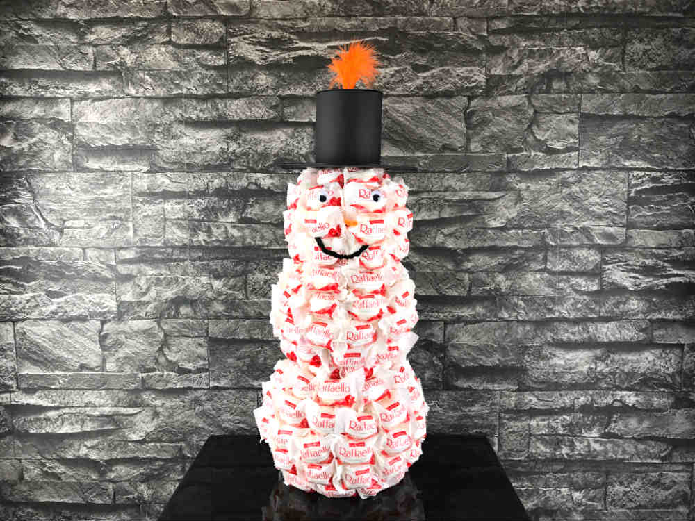 Befestige den Hut mittig auf dem Raffaello Schneemann Kopf